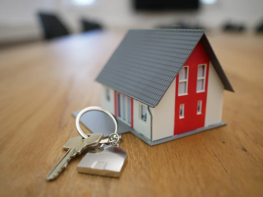 In this image, a toy house is depicted alongside real-sized keys on the table. This symbolism emphasizes the importance of having a secure and protected home. The keys, so ordinary yet fundamental, remind us that safety and stability at home are crucial for well-being and development. Every detail reflects the aspiration to provide a solid and comforting shelter for our families.